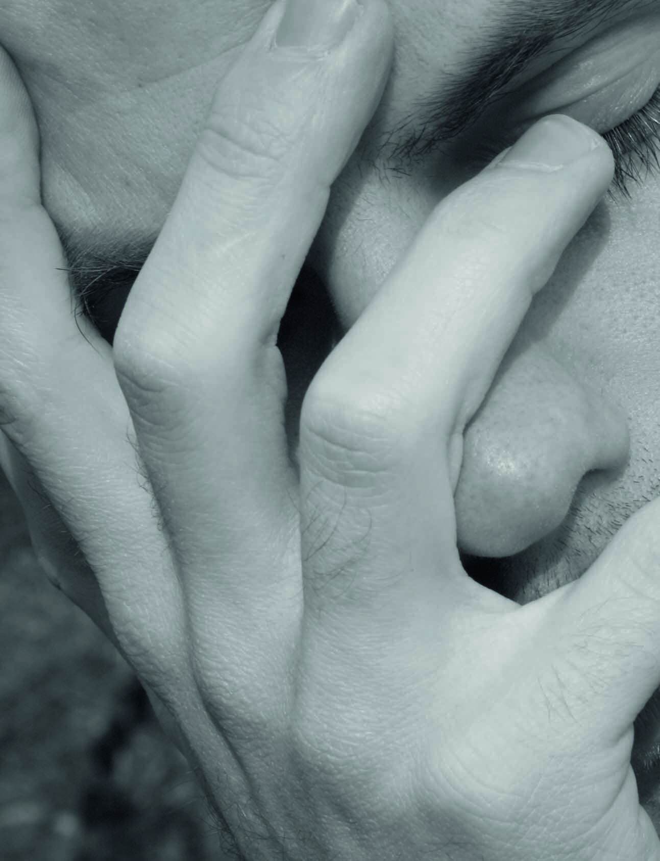 Nahaufnahme eines besorgten Gesichts, das sich mit beiden Händen die Augen verdeckt